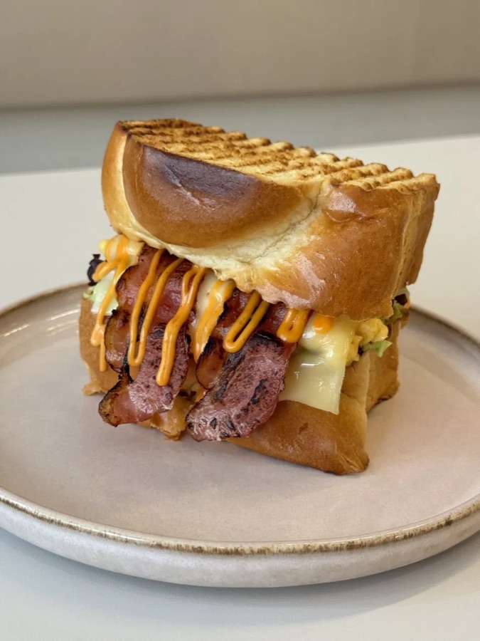 Egg Drop Sandwich mit Bacon, Käse und Chili-Mayo im gegrillten Brioche