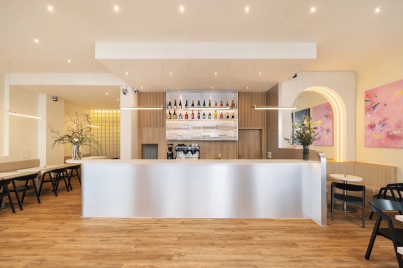 Die lange Edelstahl-Theke von lue. mit beleuchtetem Regal und Espressomaschine
